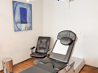 Untersuchungsraum im MVZ Goldbach Untersuchungsraum im MVZ Goldbach mit elektrisch verstellbarer Liege, schwarzem Sessel und Deckenleuchte.